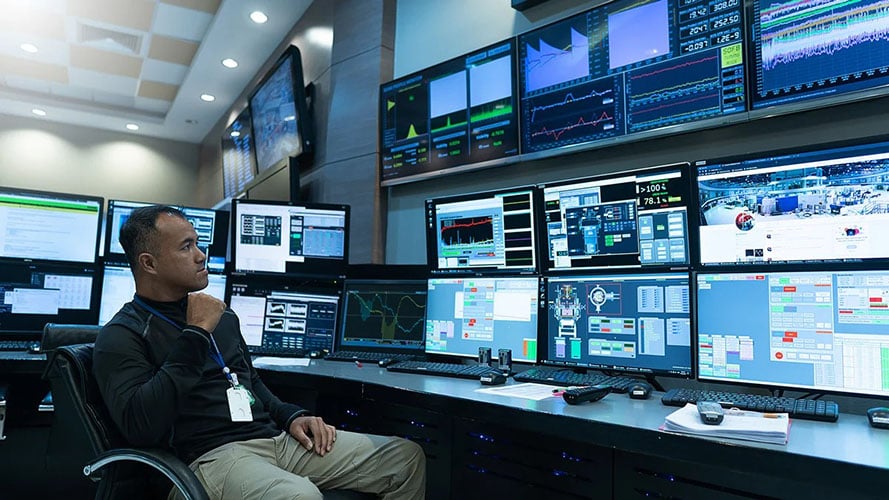 Network operations center worker monitors infrastructure through video walls