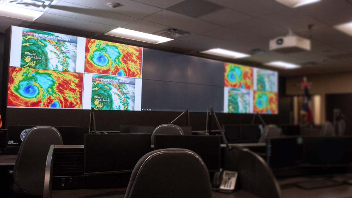 Sala de control vacía con radares meteorológicos visualizados en un gran mural de vídeo y puestos de trabajo
