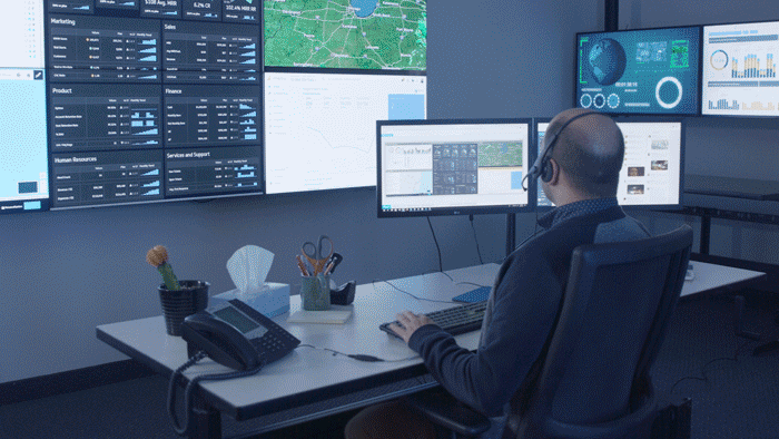 GIF de un empleado de logística tecleando en su mesa de oficina frente a un videowall, y luego a distancia desde su mesa de casa frente a una ventana