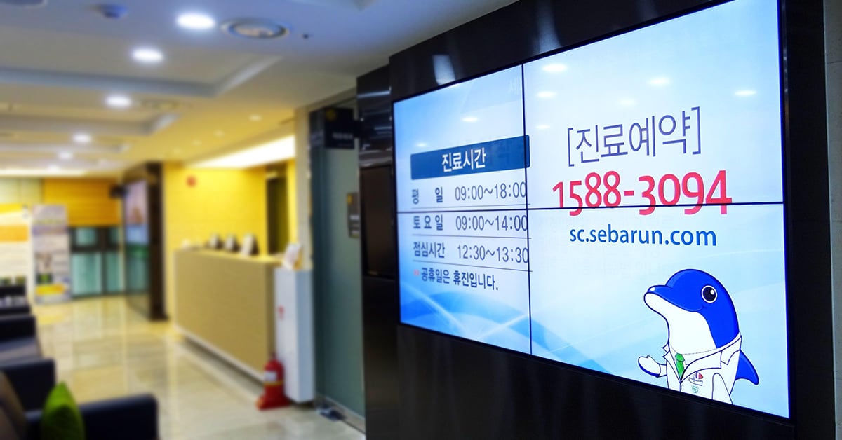 Sala de espera del Hospital Seocho Se Barun, con una pared de vídeo que muestra los horarios y los datos de contacto