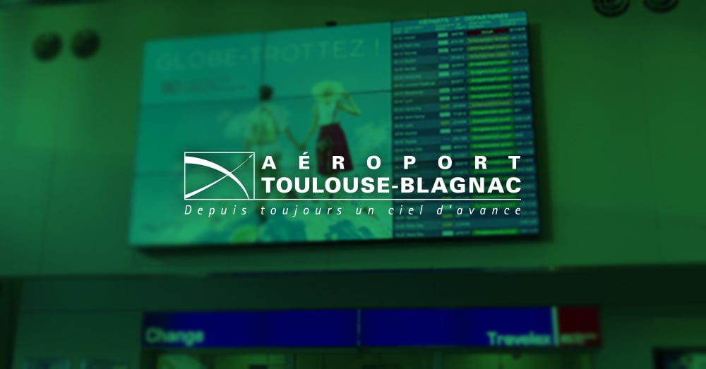 Videowall en el aeropuerto de Toulouse-Blagnac que muestra la publicidad y los horarios de salida de los vuelos con una superposición verde y el logotipo