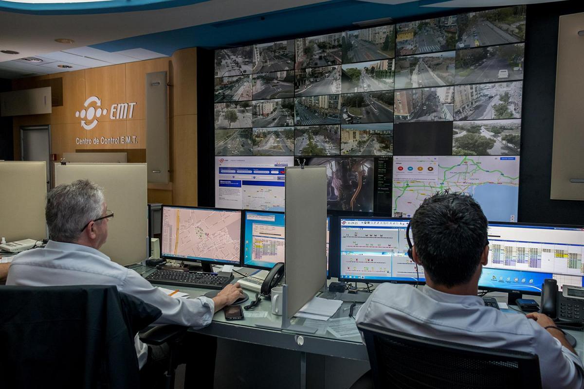 Centro de control de la EMT con trabajadores que supervisan las condiciones de tránsito a través de sus puestos de trabajo y un videowall que muestra las rutas de tránsito, imágenes en directo y datos