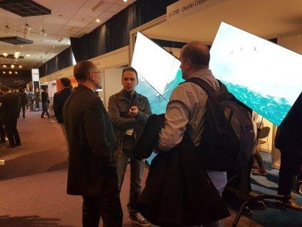 Empleados de Userful y asistentes charlan frente a un videowall de mosaico en ISE 2018 Ámsterdam