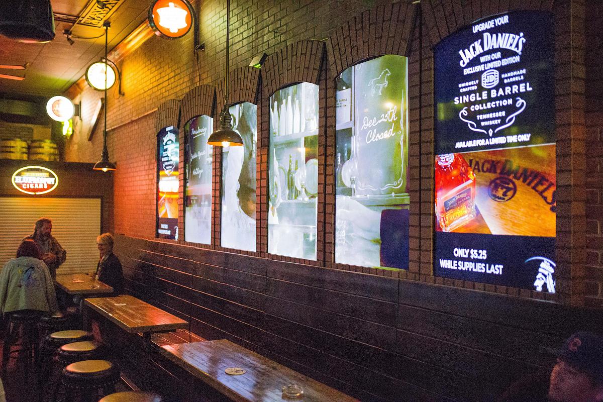Paredes de vídeo estilo ventana en el pub Smokin' Joe's, que muestran anuncios y arte visual