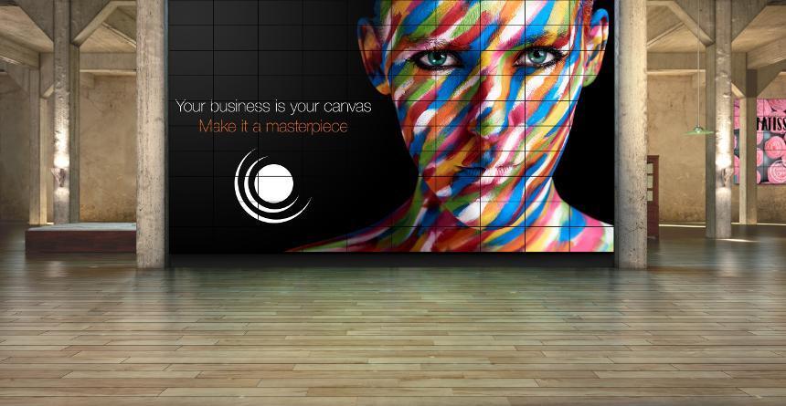 Gran muro de vídeo con la imagen de una mujer con la cara pintada de colores. El texto dice: Tu negocio es tu lienzo. Haz de él una obra maestra.