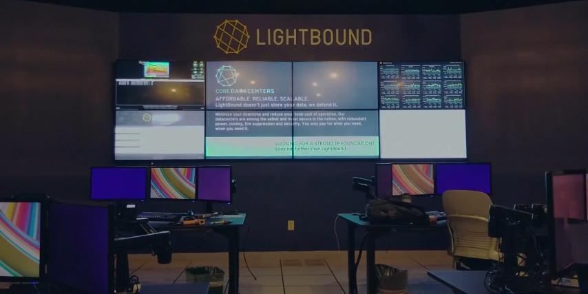 Sala de control de Lightbound vacía con 2 puestos de trabajo y un videowall que muestra páginas web, datos y publicidad