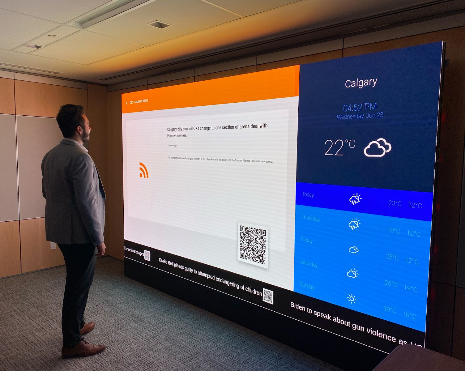 Business man watching news alerts and weather forecast on an office video wall