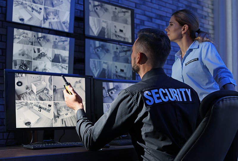 2 guardias de seguridad vigilan el interior de un edificio a través de una cámara en directo en un videowall